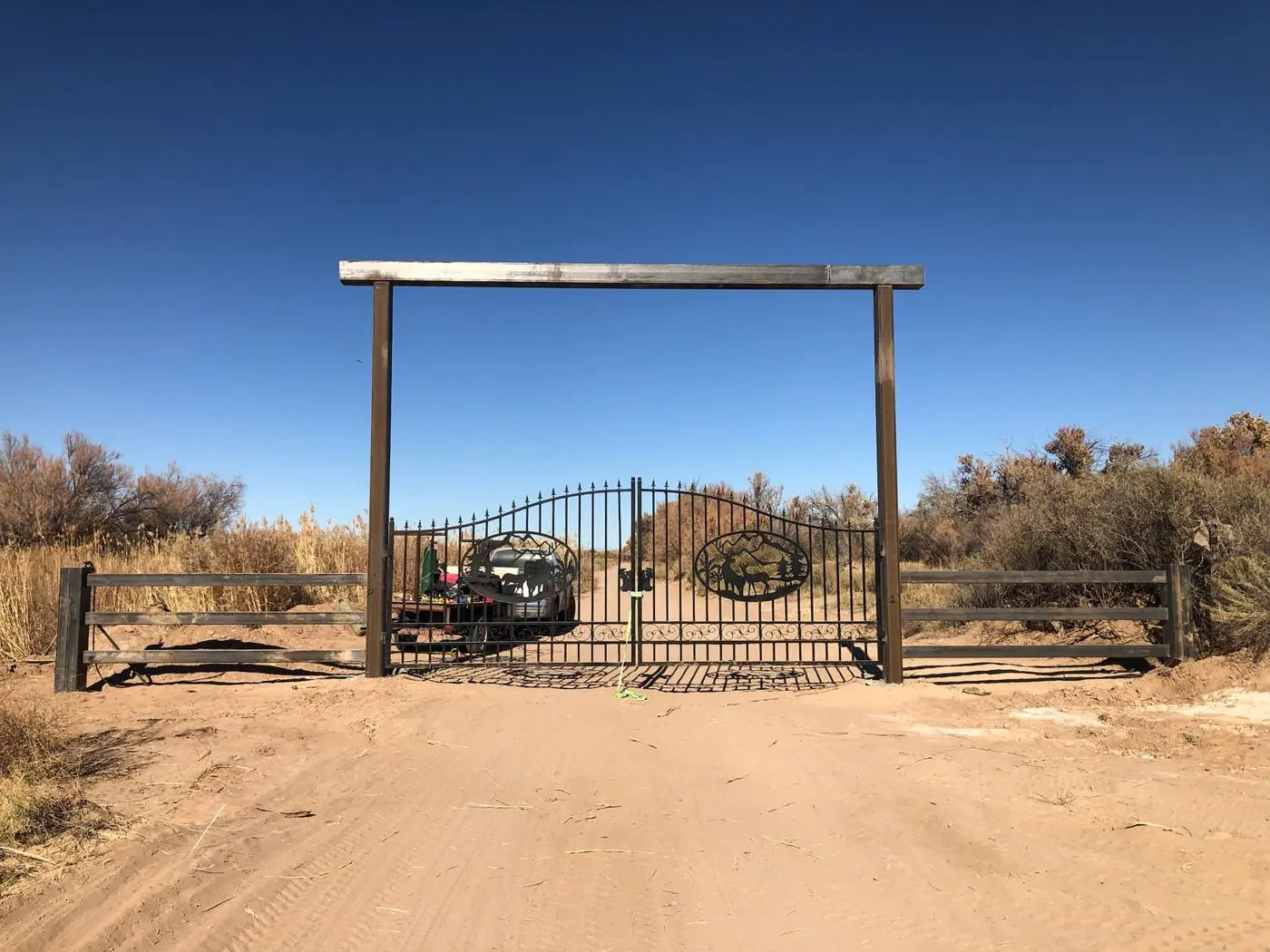 Double steel swing gates with elk cutouts under a steel entry frame