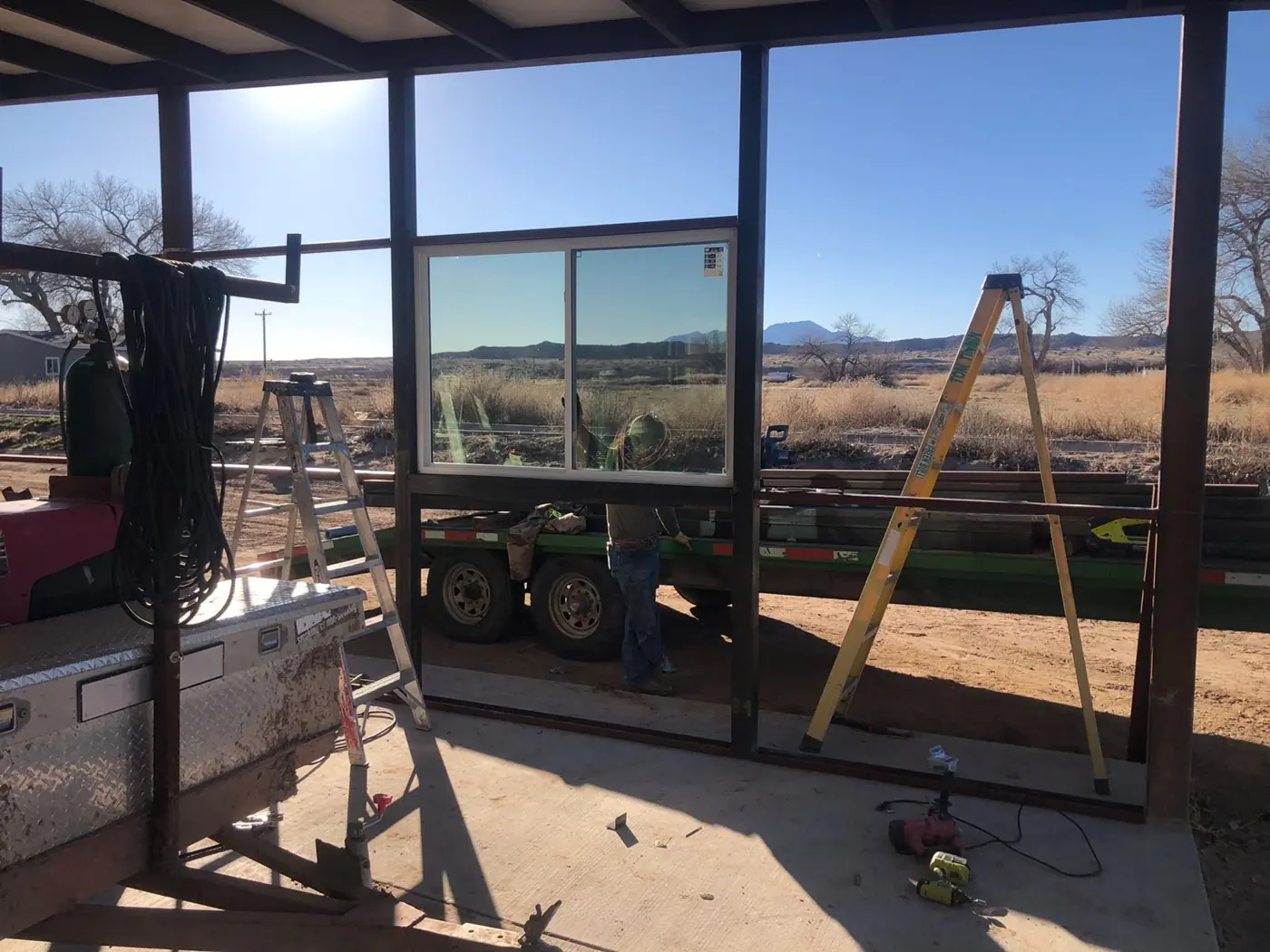 Steel-framed wall with a new window, mountains and open desert beyond