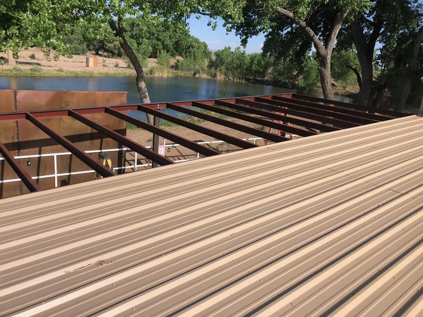 Steel roof framing off a building beside a pond
